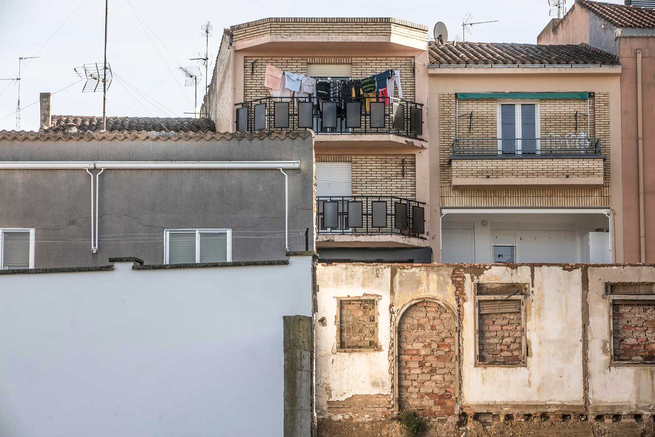 Vista de la fachada de una casa, donde se ve el tendedero lleno de ropa tendida en la terraza