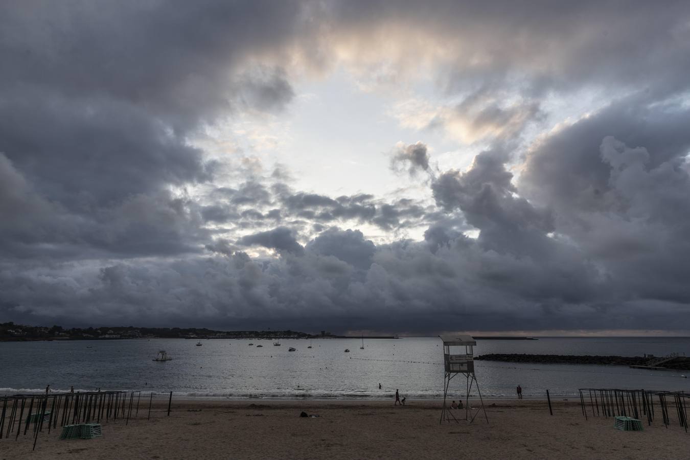 La fotógrafa, frente al teatro del mar, captura la escena en la que los grandes telones de nubes pintadas se van ocluyendo, como un diafragma en el objetivo de la cámara, en vías del momento culminante de la apoteosis del día