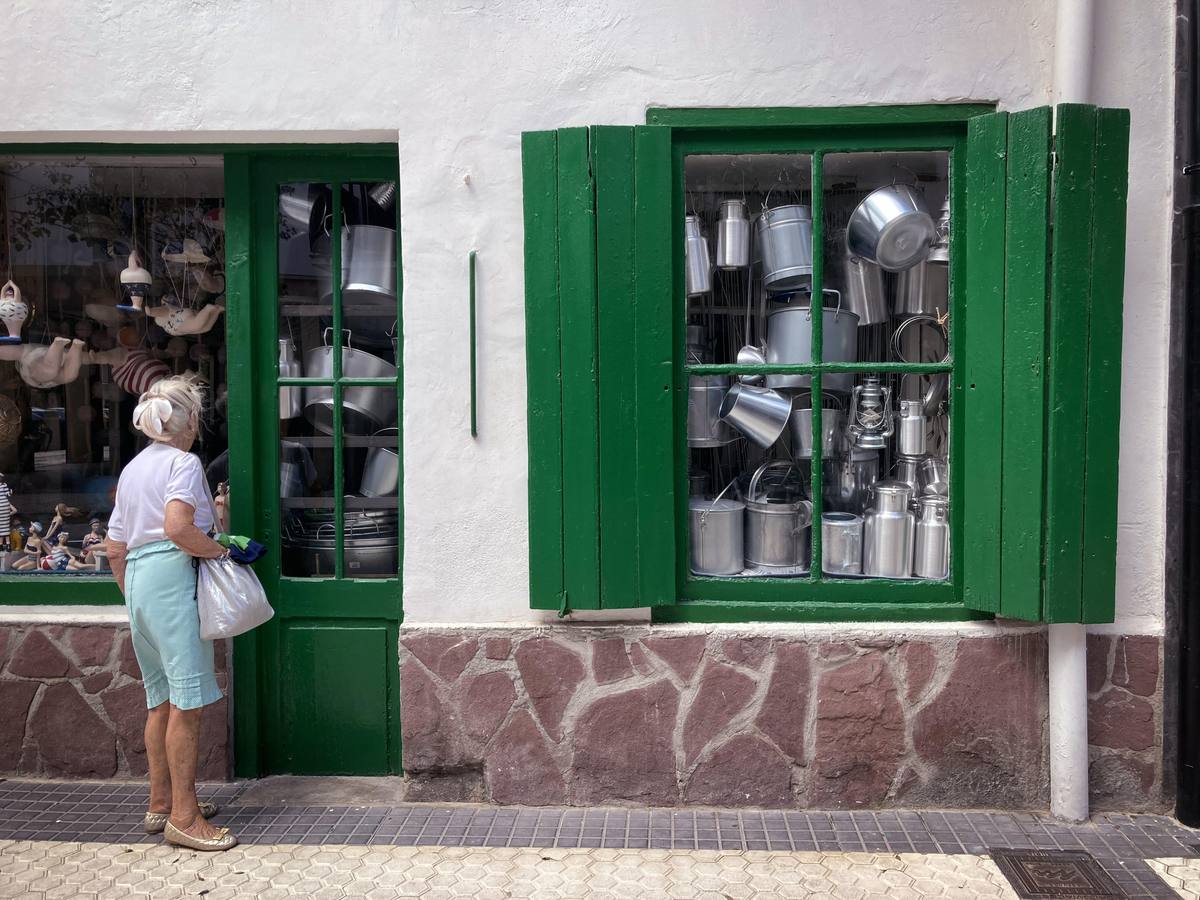 Mujer frente al escaparate de una tienda de artículos para el hogar: ollas, cazuelas, cubos...